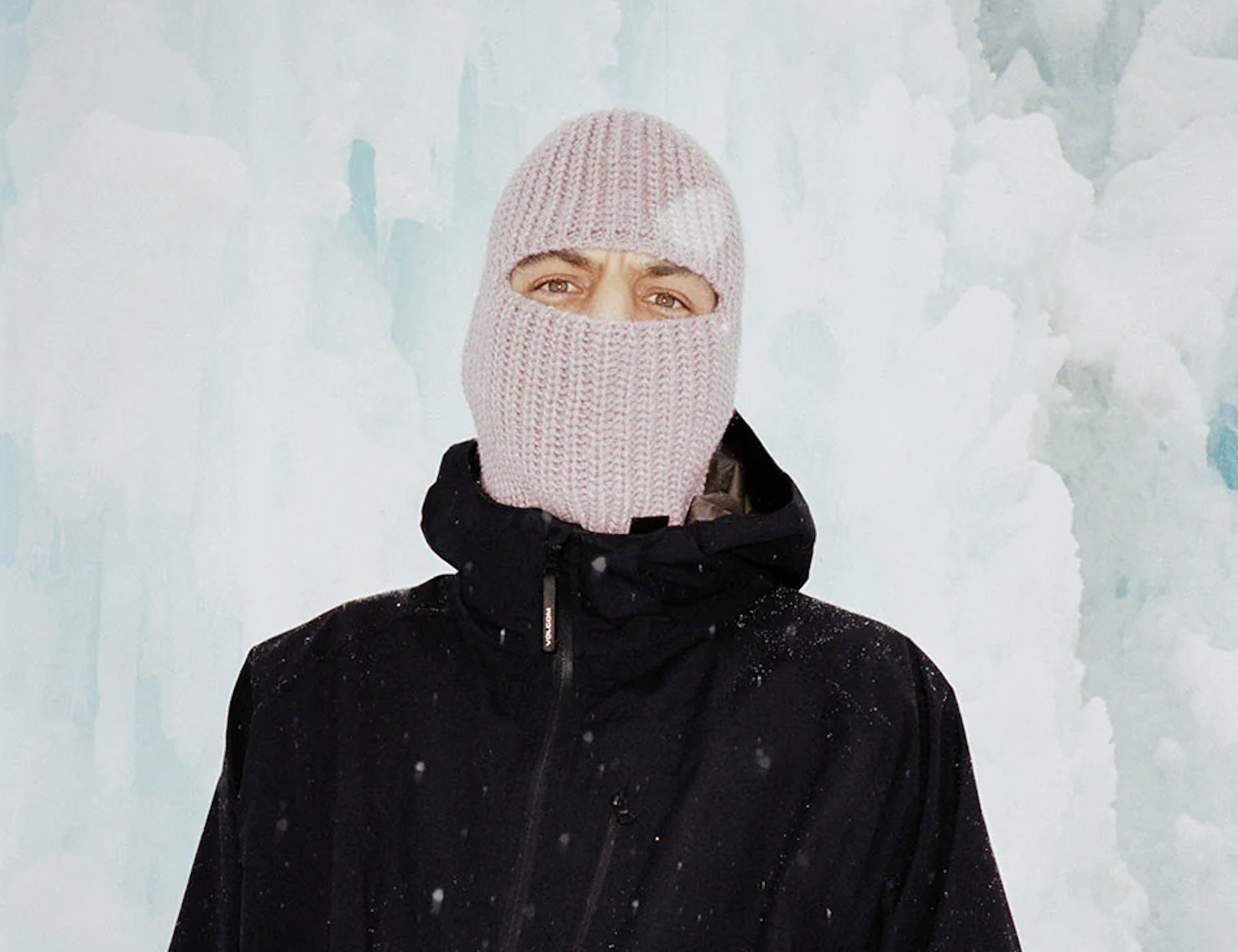 HAE Wear Sturmhaube Ein Mann mit einer einer rosanen HAE Sturmhaube steht vor einem Gletscher