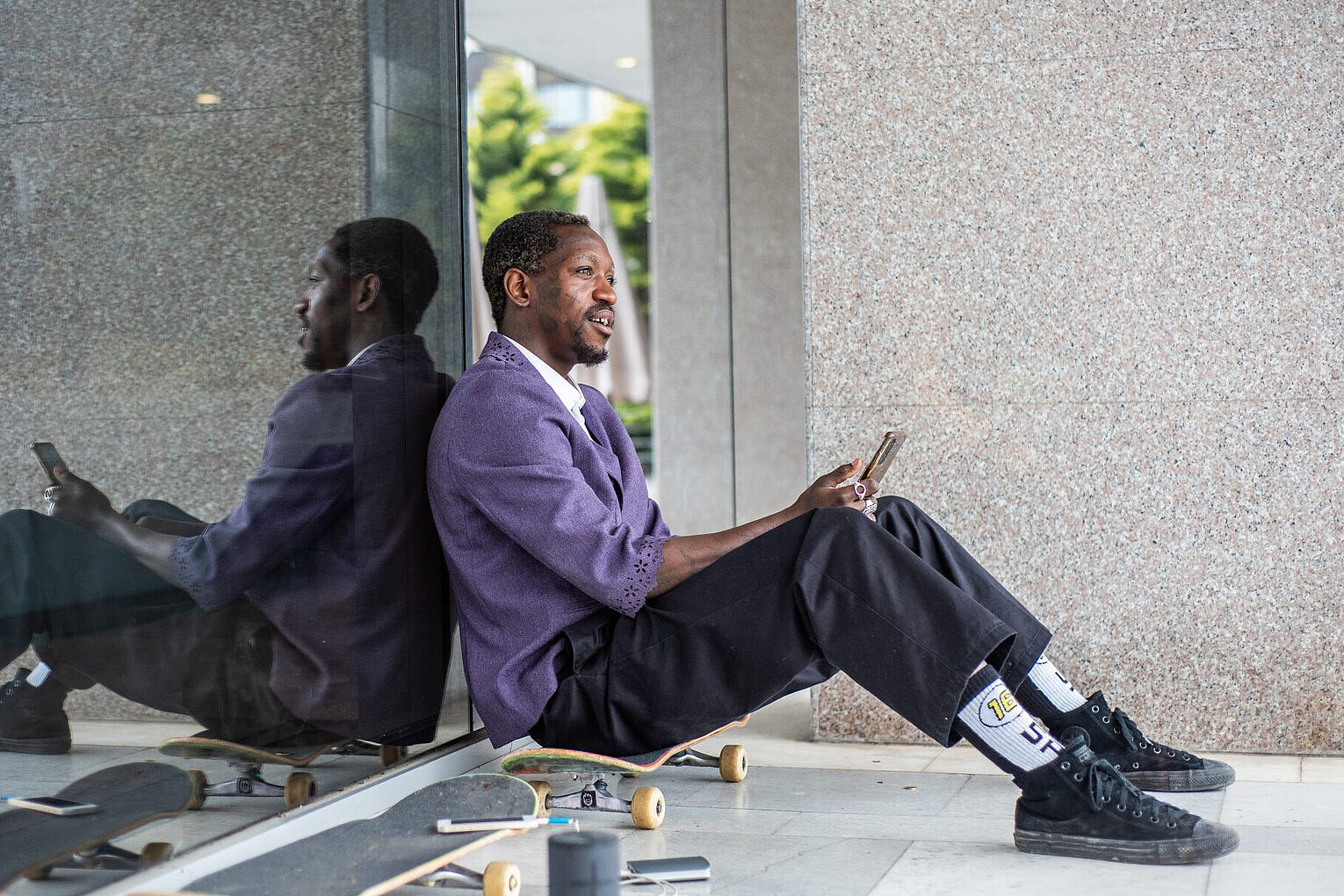 Stinky Socks Sportsocken Ein Skateboarder sitzt auf seinem Board und hält sein Handy in der Hand